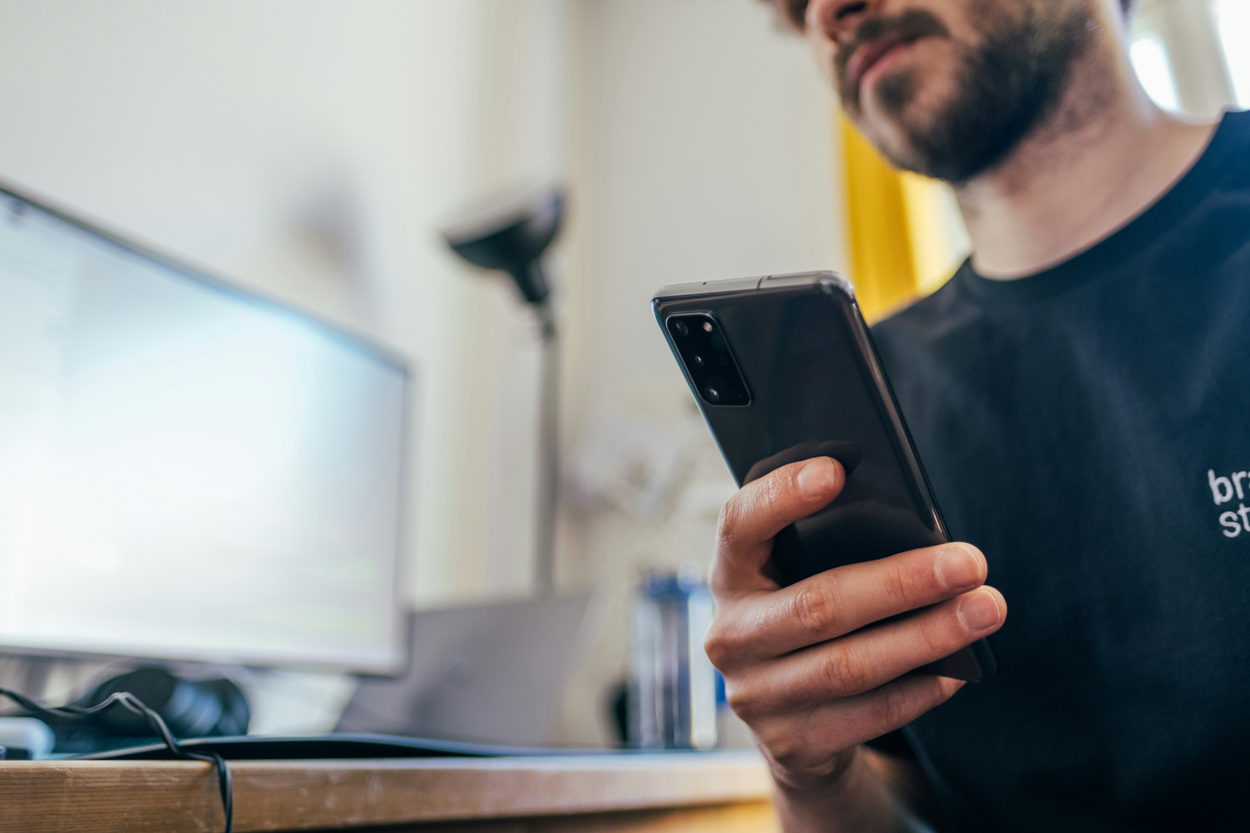 man in black crew neck shirt holding black iphone 5